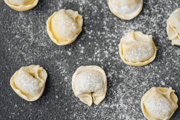 Closeup of scattered flour dusted cappelletti pasta on kitchen counter