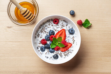 Chia bowl with yogurt, berries and honey on wooden table
