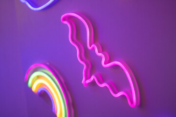 Naklejka premium Vibrant neon bat sign on purple wall