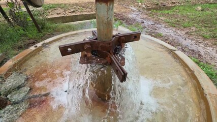 water gushing freely from a borewell without any motor or pump. The underground pressure is strong enough to push the water up to the surface on its own
