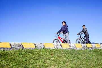 Two Men Pushing A Bicycle On A Sunny Day