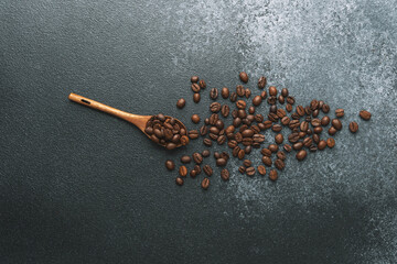 Coffee beans in wooden spoon on dark background
