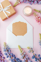 Gift box and envelope with card and flowers on pink background