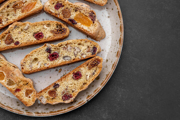 Italian Almond Biscotti biscuits in a rustic home made pottery bowl. Studded with almonds and cranberries, these twice-baked treats are aromatic and inviting. Ideal.