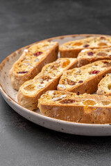 Italian Almond Biscotti biscuits in a rustic home made pottery bowl. Studded with almonds and cranberries, these twice-baked treats are aromatic and inviting. Ideal.
