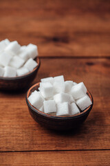 Square sugar cubes presented in decorative bowls on wooden table surface