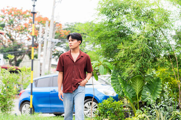 A thoughtful young asian man in a standing pose with one hand in his pocket, gazing far into the...
