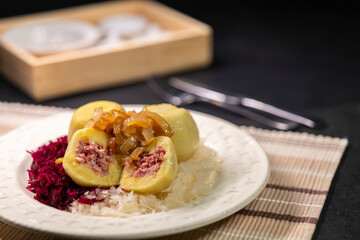 Potato dumplings filled with minced meat, topped with fried onions, served with sauerkraut and red cabbage