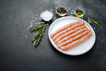 Fresh pork sausages on white plate with herbs and seasonings