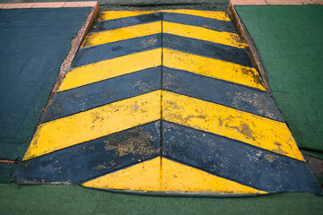 Road speed bump with black and yellow striped pattern on urban street crossing area