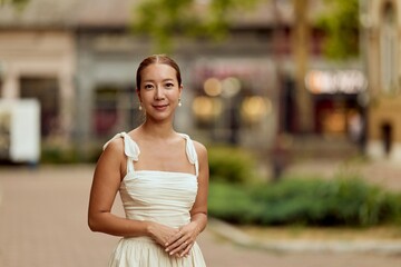 Elegant Woman in White Dress Standing Outdoors on a Bright Day