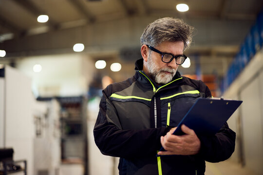 Industrial Manager Reviewing Checklist in Modern Manufacturing Facility