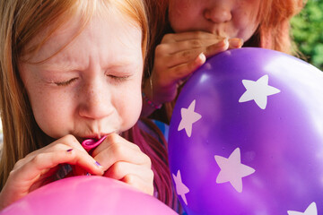 Children blowing up colorful balloons with joy and determination