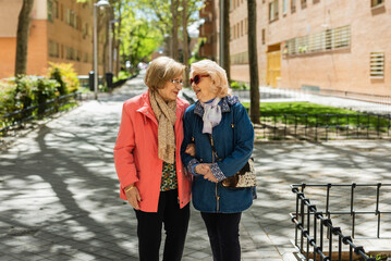 Two senior women walking and talking outdoors in an urban setting
