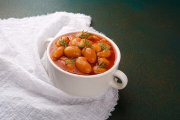 Cooked white beans in tomato sauce with dill in ceramic bowl for vegan meal, lunch or comfort food