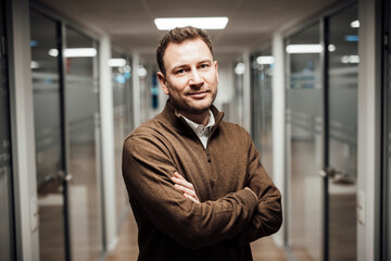 Confident professional standing in modern office hallway research setting