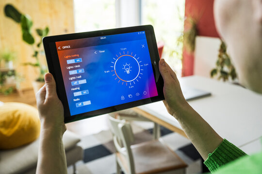 Person using smarthome app on tablet to control lights indoors