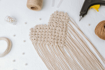 Heart macrame with glue gun and cord on white background