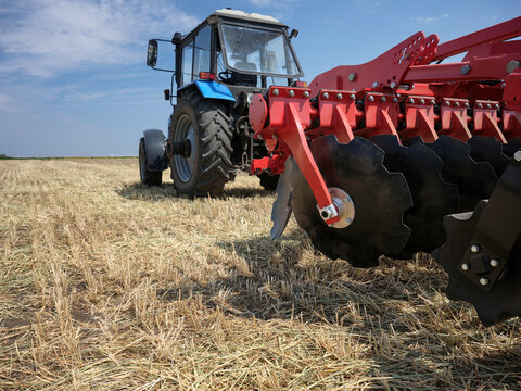 Large industrial disk plow red color for tilling soil in the field.