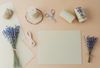 Candle making supplies and lavender flowers on beige surface flat lay