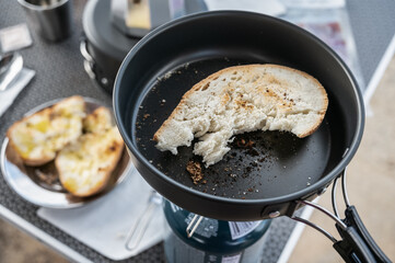 Camper cooking bread on portable gas stove during camping trip