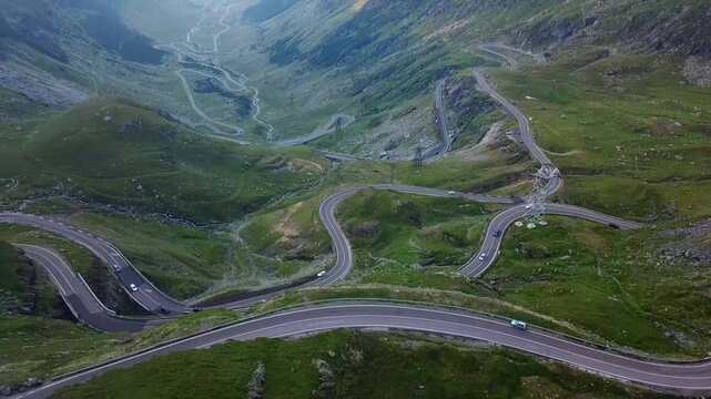 Transfagarasan Road winds through a lush, green valley, surrounded by the Carpathian Mountains