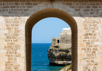 Polignano a Mare, Italy. Beach between the rocks. View of the sea and the beach. Old buildings on a cliff by the sea. Italian architecture. Photos for backgrounds, wallpapers, postcards.