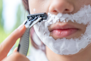 Young teenage boy 13 years old trying first shave, growing up, puberty beginning, shaving foam,...