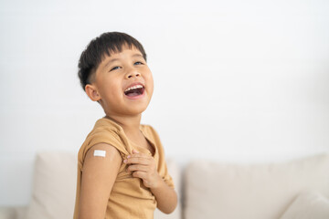 Portrait of happy smile vaccinated little asian kid boy children ages 5 to 11 years old posing show arm with medical plaster after Injection vaccine Covid-19 protection.coronavirus vaccination kid