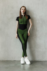 Fototapeta premium young girl in a tracksuit on a wall background. Free space for text. Wide angle vertical wallpaper or web banner.