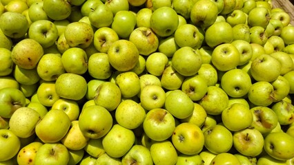 Fresh organic green apples piled high at a farm market stall. Crisp texture, vibrant color, and natural shine—perfect for healthy eating and natural produce themes