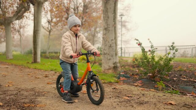 Young child enjoying a joyful ride on a balance bike.