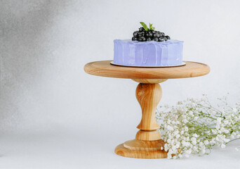 Lavender blueberry cake on a wooden stand with delicate flowers