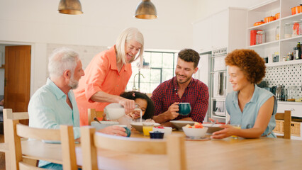 Multi-Generation Family At Home Enjoying Breakfast Sitting Around Table Together