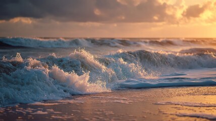 Fototapeta premium Waves roll onto the sandy shore as the sun sets, casting warm colors across the water.