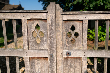 Weathered wooden gate with decorative cutouts in a rustic outdoor setting, evoking countryside charm and vintage style.