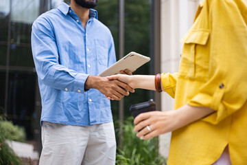 Business partners shaking hands outside a building, symbolizing agreement and collaboration.