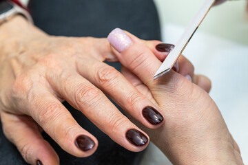 Nail care procedure in a beauty salon. Female hands and tools for manicure, process of performing...