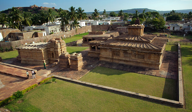 Aerial view of ancient stone temples standing proudly amidst manicured lawns and pathways, Badami, Karnataka, India.