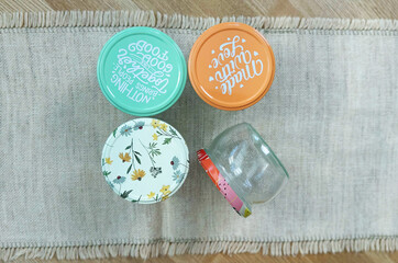 Empty glass jars with colorful patterned lids for preservation, preparations for winter, arranged...
