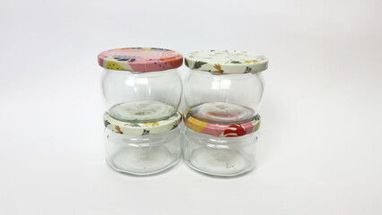 Empty glass jars with colorful patterned lids for preservation, preparations for winter, arranged in different compositions on fabric and white background, top view and front view, food storage contai