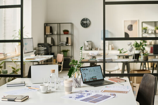 Selective focus interior shot of modern office with laptops, computers and papers on desks, copy space