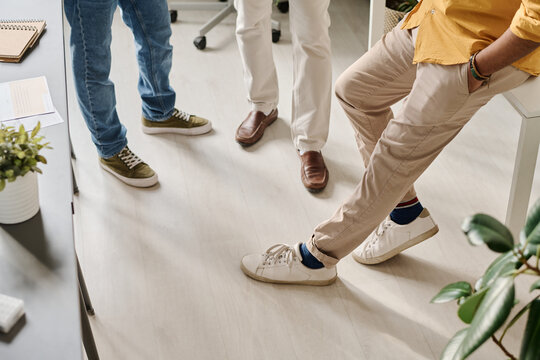 High angle view of legs of unrecognizable male managers during break time in modern office