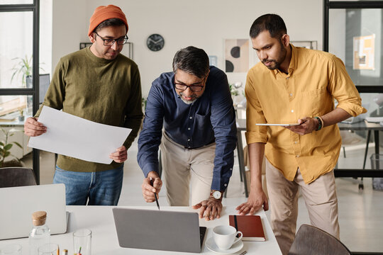 Medium long shot of three South Asian men working together on business strategy in modern office