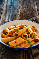 Creamy tomato and stracciatella pennone rigato noodles on wooden table