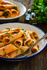 Creamy tomato and stracciatella pennone rigato noodles on wooden table