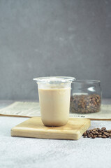 Ice coffee in a plastic cup with brown sugar and ice cubes and beans