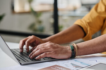 Closeup of unrecognizable mans hands typing on laptop at work in modern office, copy space
