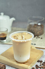 Ice coffee in a plastic cup with brown sugar and ice cubes and beans