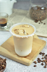 Ice coffee in a plastic cup with brown sugar and ice cubes and beans